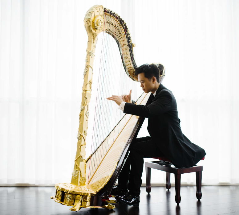 Andrew playing a gold concert harp